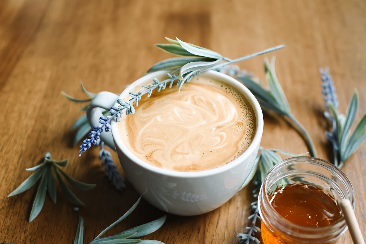 Delicious cappuccino adorned with lavender next to a jar of honey, creating a cozy vibe.